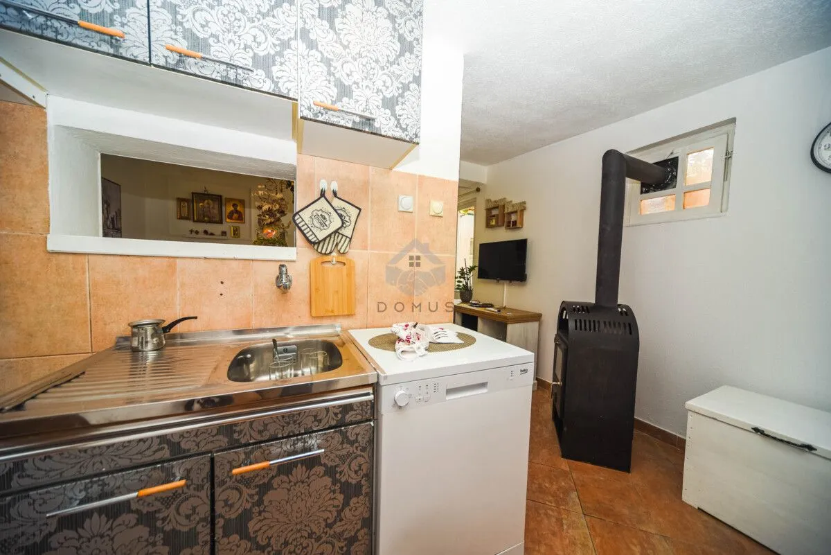 Small kitchen with a sink, dishwasher, and wood-burning stove.
