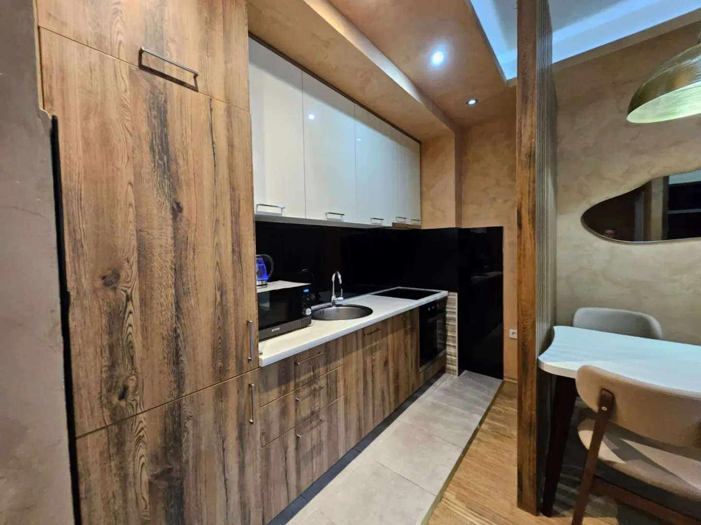 Modern kitchen with wooden cabinetry and white upper cabinets.