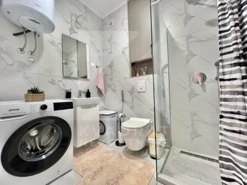 Modern equipped bathroom with a walk-in shower and washing machine. - image 8