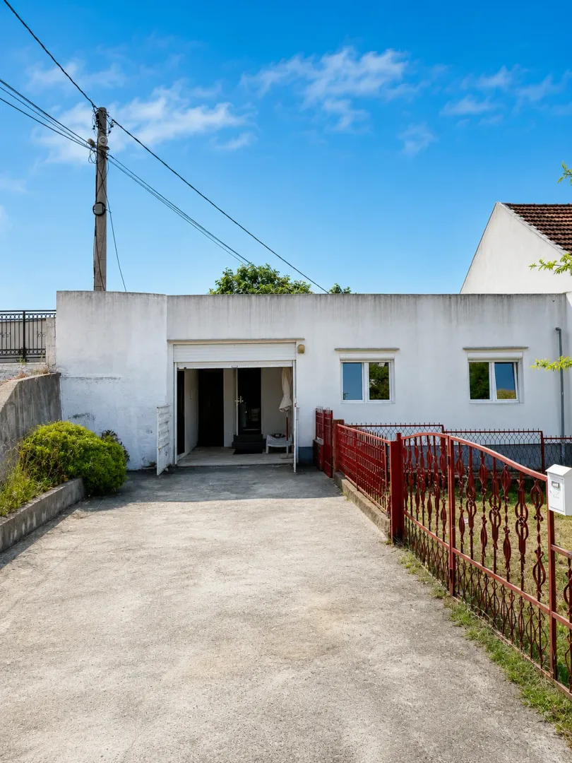 View of the yard and ground floor of the house with a driveway.