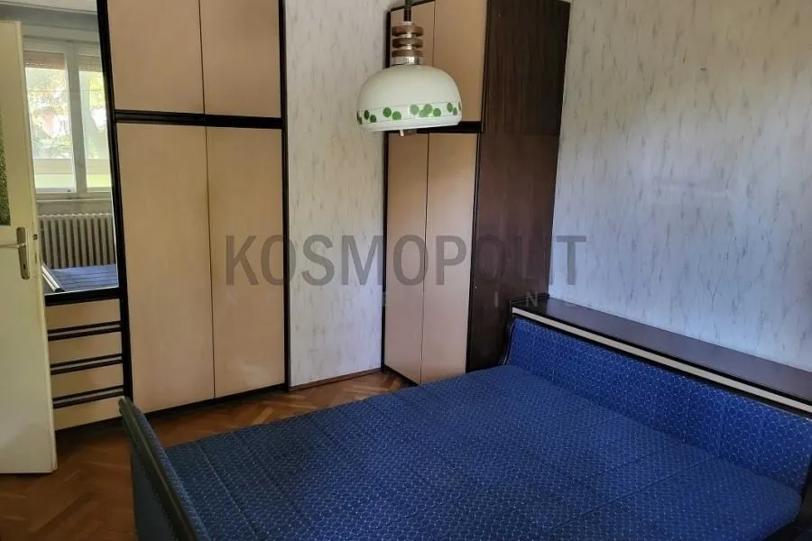 Nameštena spavaća soba sa bračnim krevetom i ugradnim ormarima.