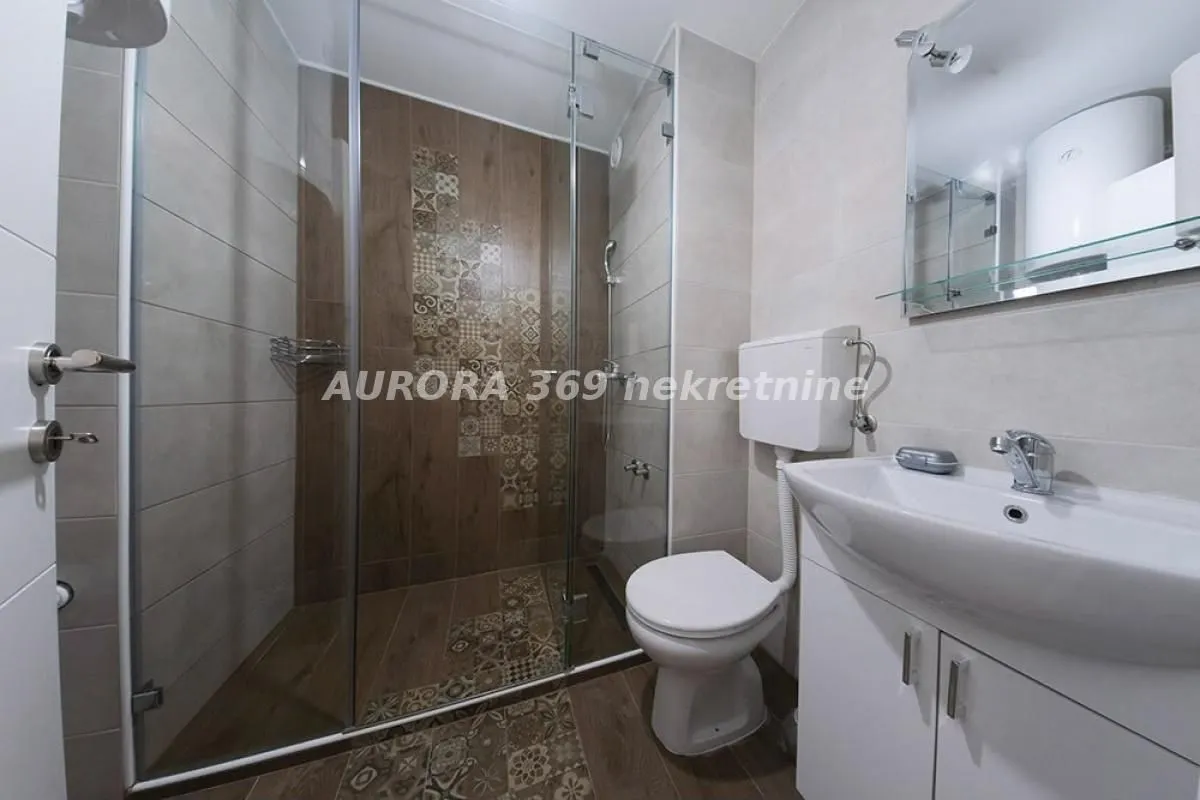 Modern bathroom with a walk-in shower, washbasin, and toilet.