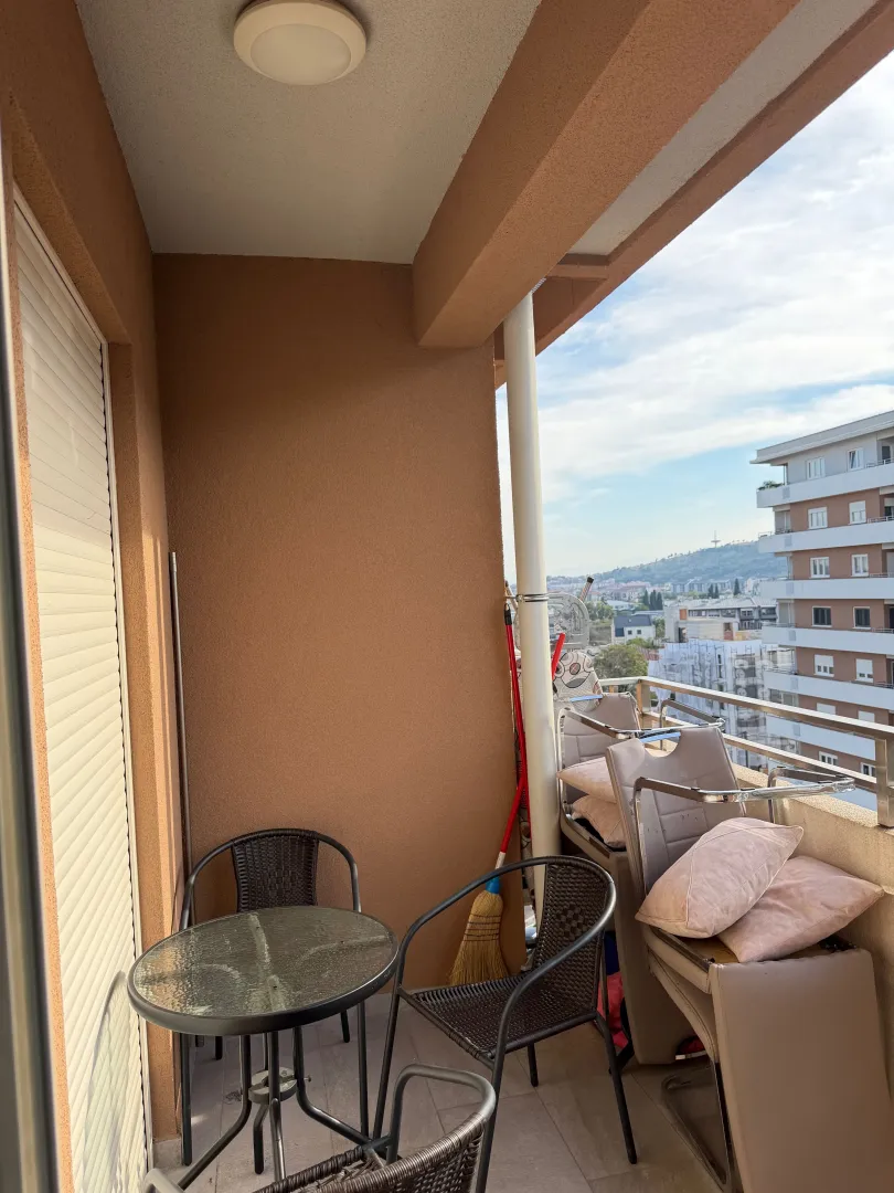 Covered balcony space with outdoor seating furniture and city view.