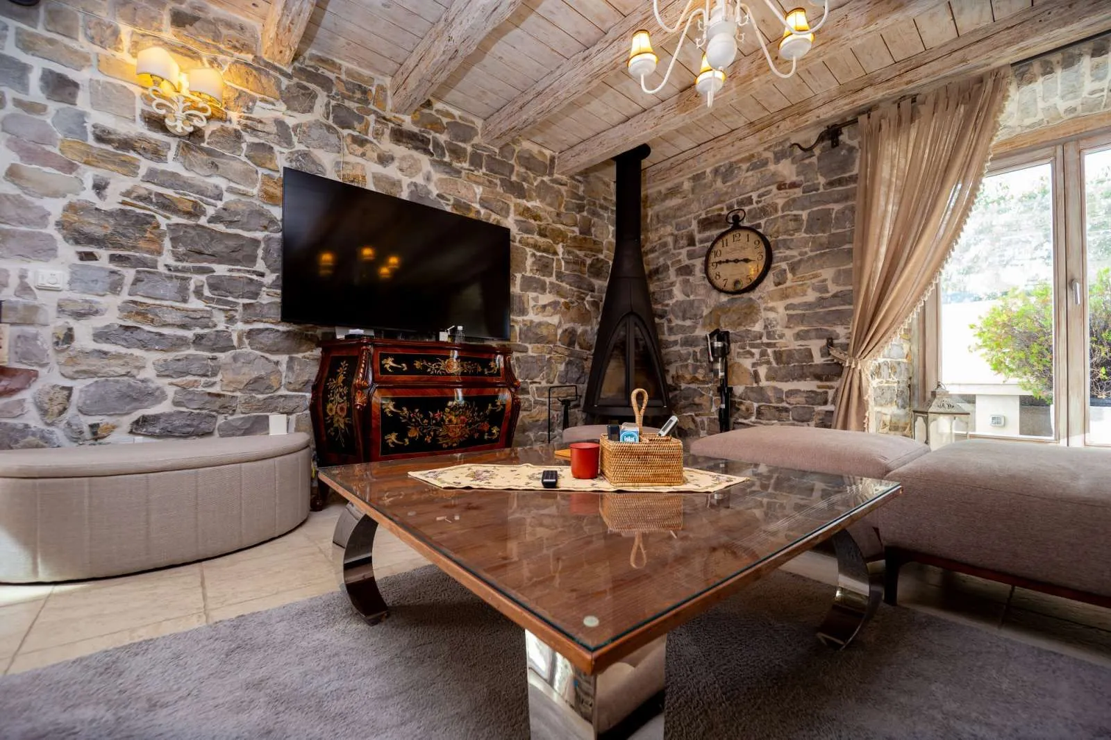 Living room with stone walls, fireplace, and wooden ceiling.