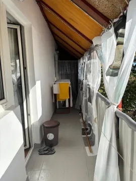 Dugi natkriveni balkon sa sušilicom za veš i zavesama duž ograde. - image 9