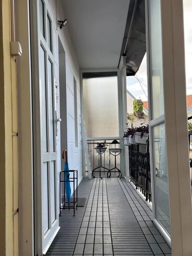 Zastakljeni balkon sa podom od pločica i držačem za kišobrane.