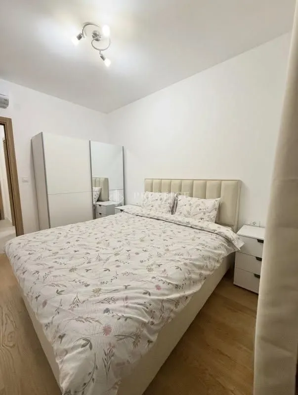Furnished bedroom with a double bed, white wardrobe, and nightstands.