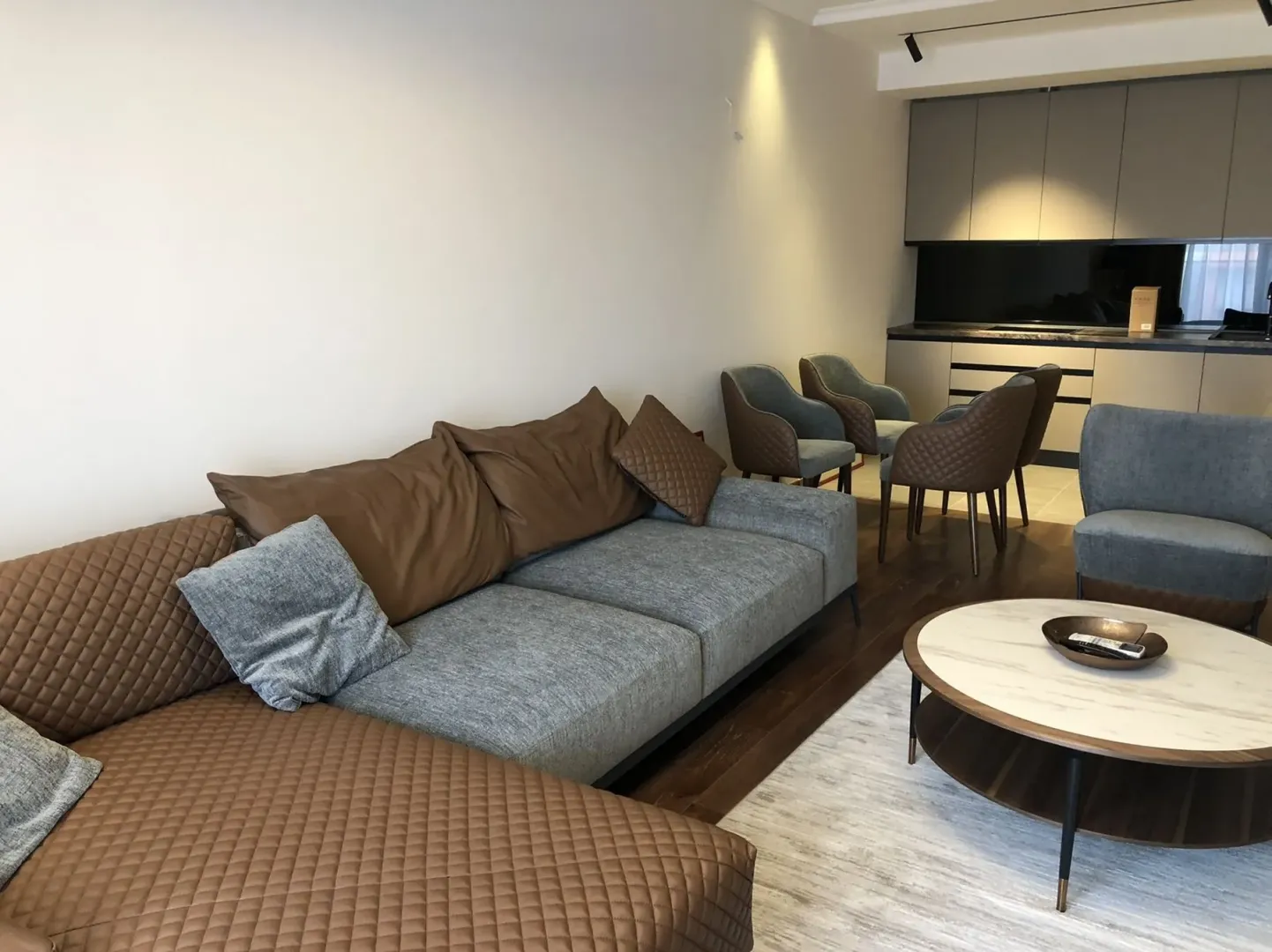 Modern living room with a spacious sectional sofa, coffee table, and dining area in the background.