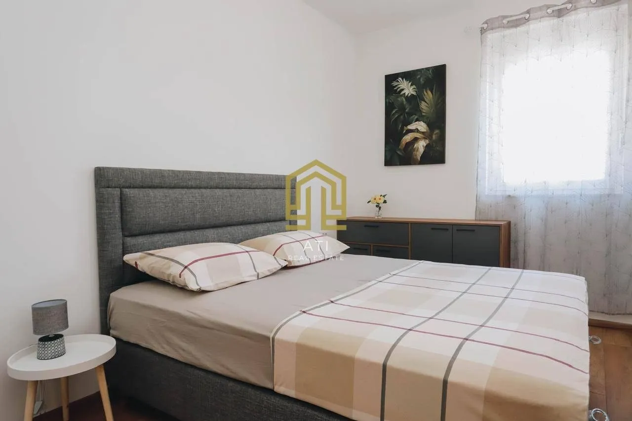 Uređena spavaća soba sa bračnim krevetom i komodom.