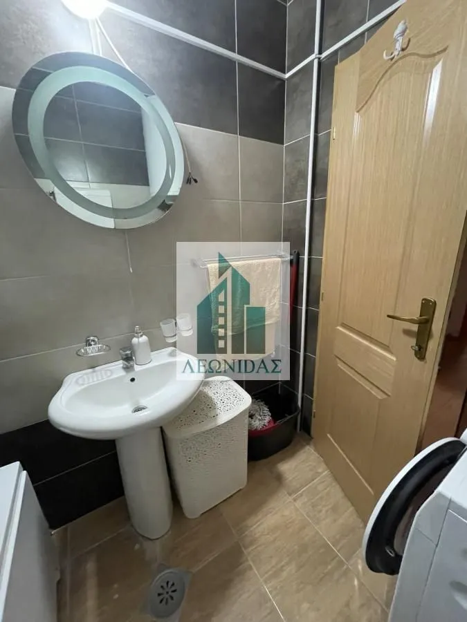 Bathroom with a washbasin, mirror, and wooden door.