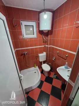 Bathroom tiled in orange with a shower cabin, toilet, and washbasin. - image 13