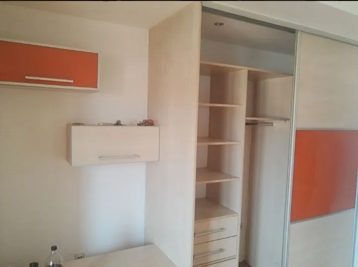 Ugradni plakar sa kliznim vratima i narandžastim detaljima.