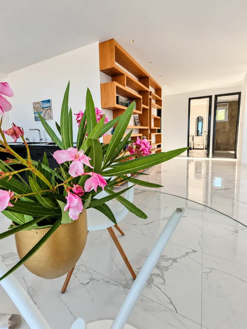 Modern interior featuring a large wooden bookshelf and decorative flowers in the foreground.