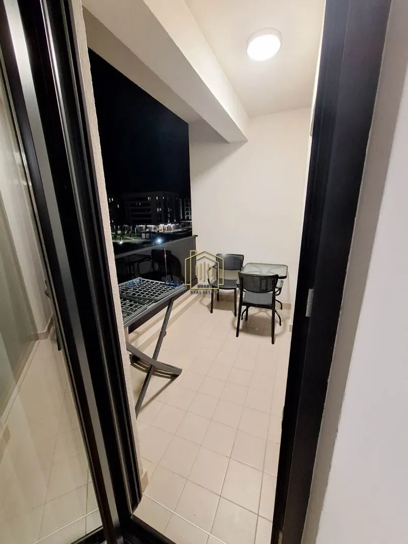 Covered terrace with a table, chairs, and a drying rack at night.