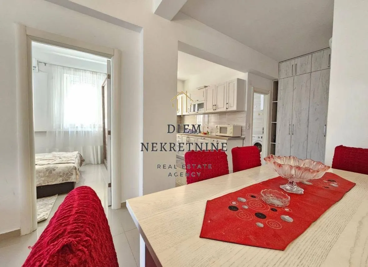 Living room with a dining table and a view of the kitchen.