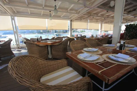 Covered restaurant terrace with wicker furniture and a sea view. - image 7