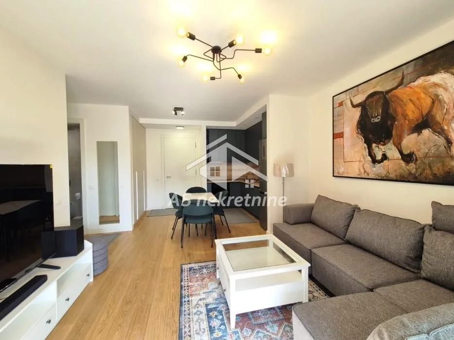 Living room with a corner sofa, TV unit and a dining area in the background.