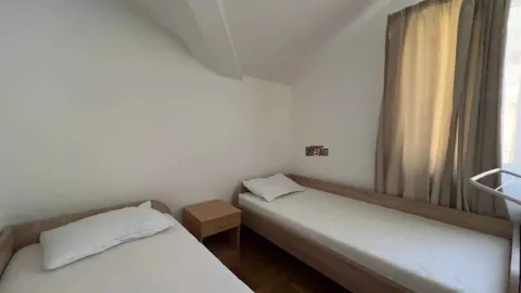 Spavaća soba sa dva odvojena kreveta i noćnim stočićem. - image 8