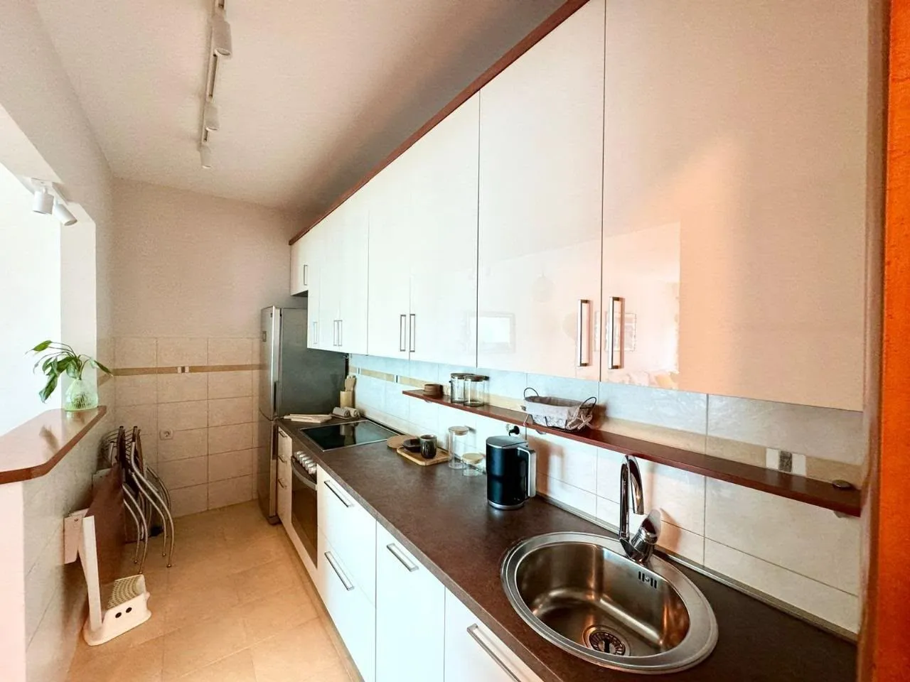 Smaller equipped kitchen with white cabinets and a sink.