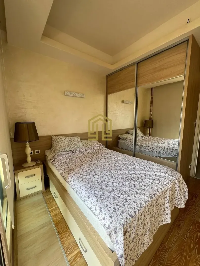 Furnished bedroom with a double bed and a mirrored built-in wardrobe.