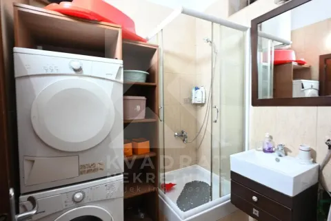 Bathroom with a shower cabin, washbasin, mirror, and washing and drying machines. - image 12