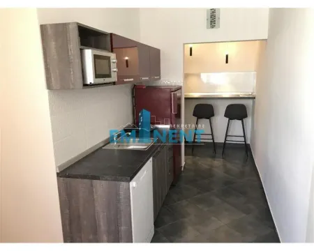 Small equipped kitchen with a breakfast bar and bar stools. - image 9