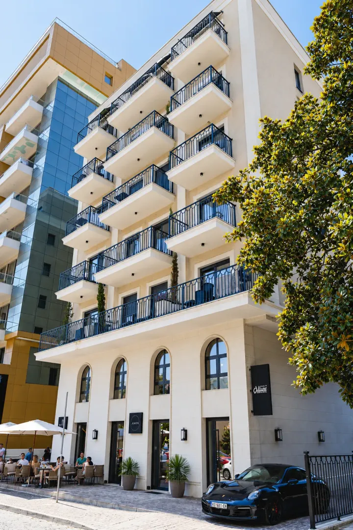 Exterior view of a modern residential building with balconies and ground floor commercial space.
