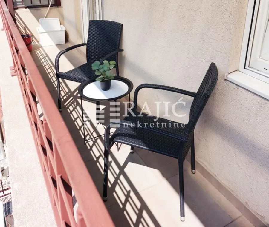 Small balcony furnished with black wicker chairs and a small table.
