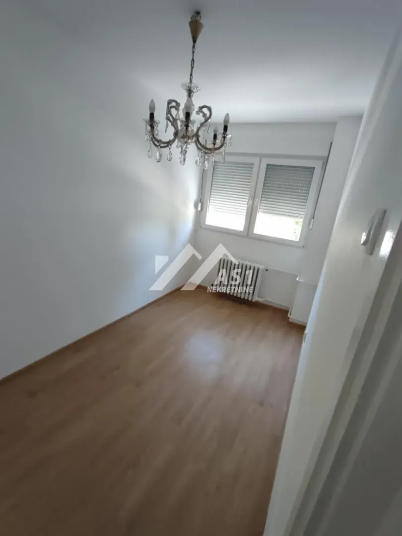 Prazna soba sa laminatom i lusterom.