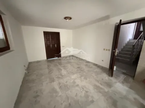 Prazna prostorija sa pločicama na podu i vratima koja vode u hodnik sa stepeništem. - image 10