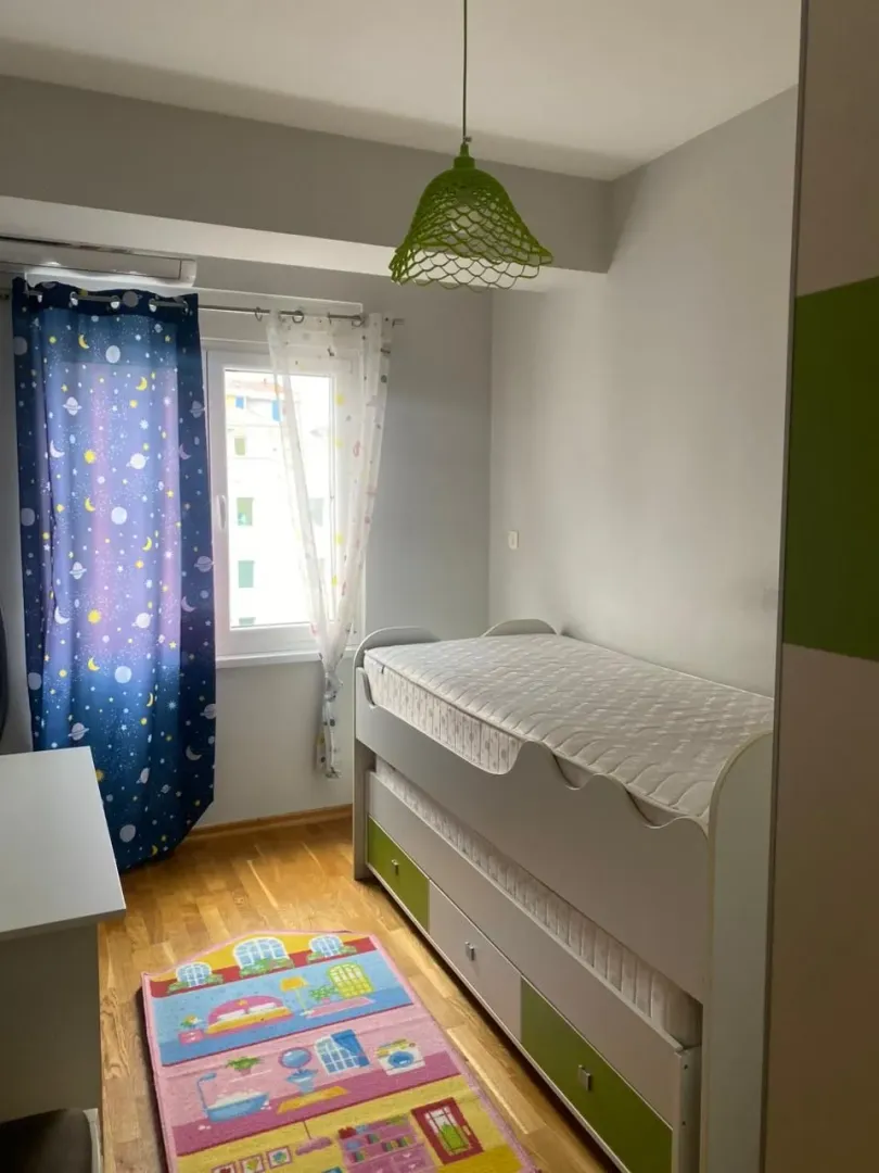 Dječja soba sa krevetom, prozorom i zelenom lampom.
