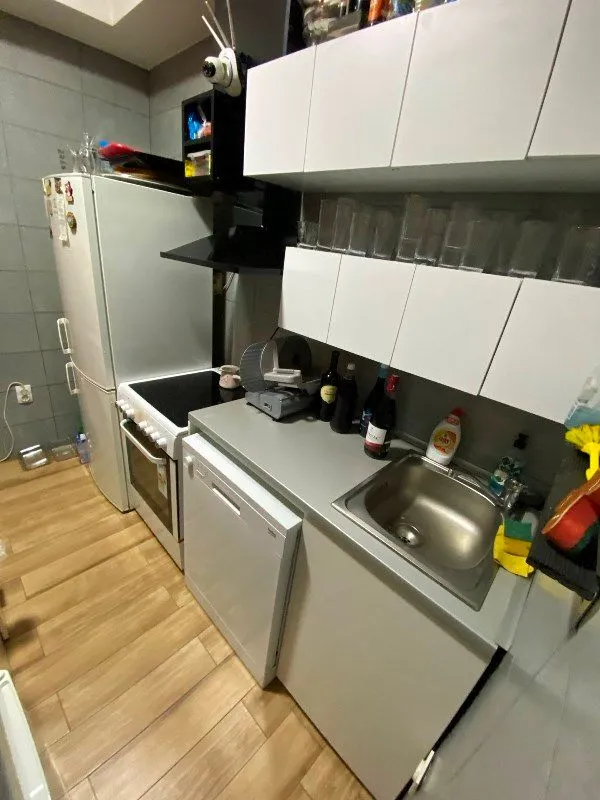 Small kitchen with white cabinets, refrigerator, and stove.
