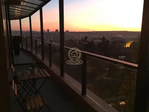 Glazed terrace with seating furniture and a city view at dusk. - image 9