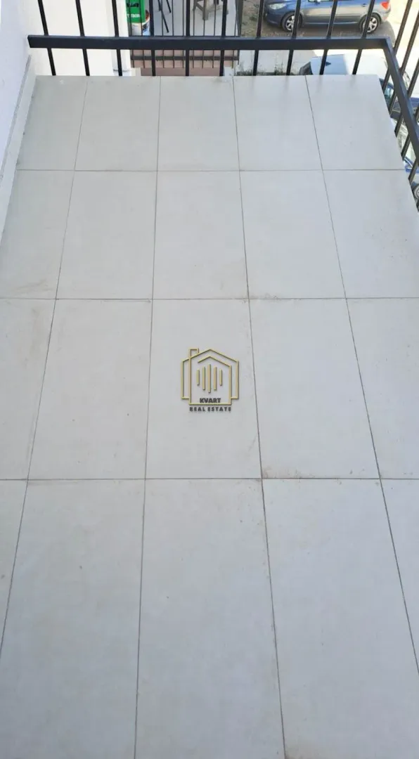 Popločani balkon sa crnom ogradom.