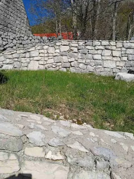 Kameni potporni zidovi i travnati dio placa sa drvećem u pozadini. - image 10