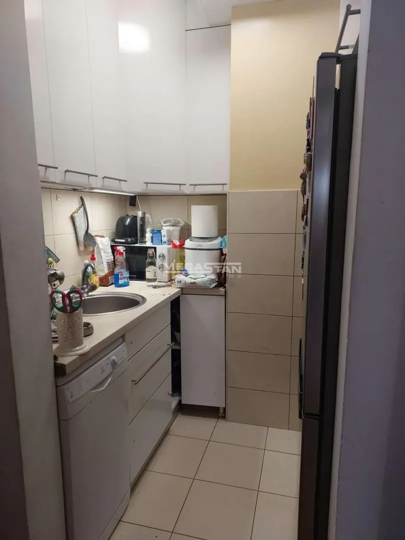 Smaller kitchen with white cabinetry and a sink.