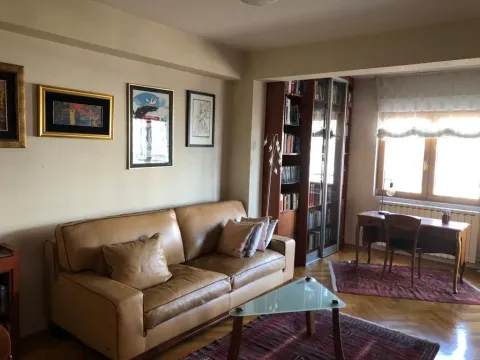 Bright living room with a leather sofa and a study desk by the window. - image 6