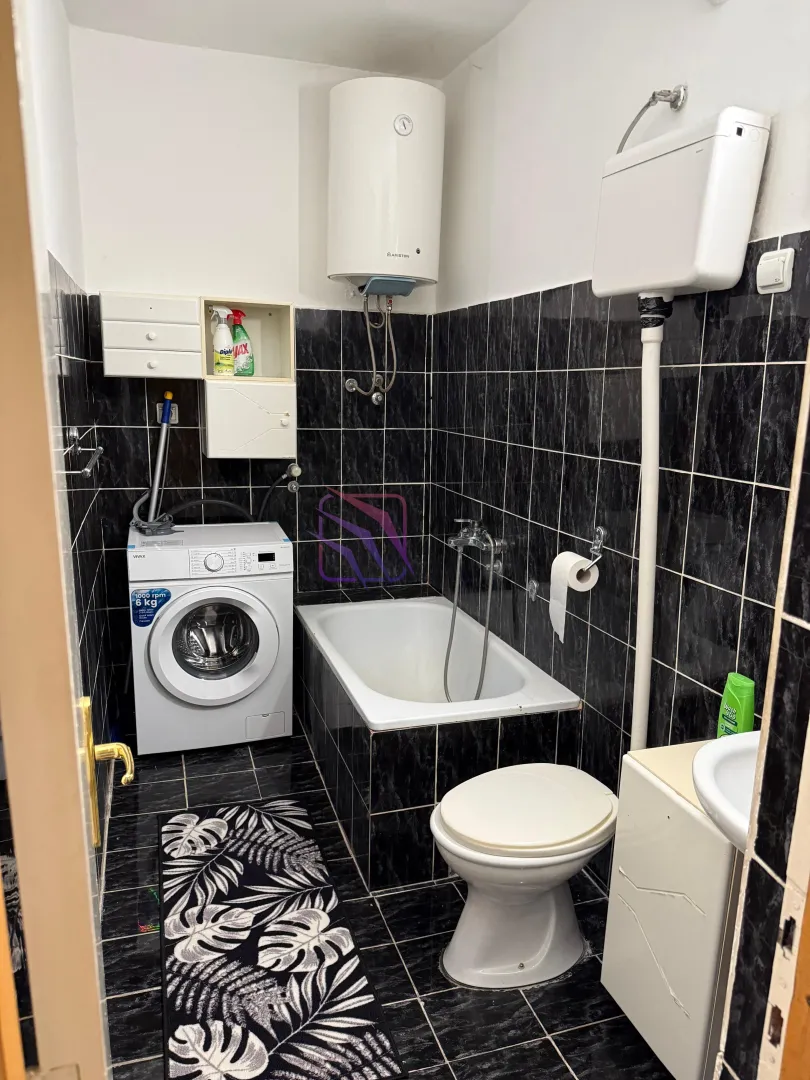 Bathroom equipped with a bathtub, washing machine, toilet, and washbasin.