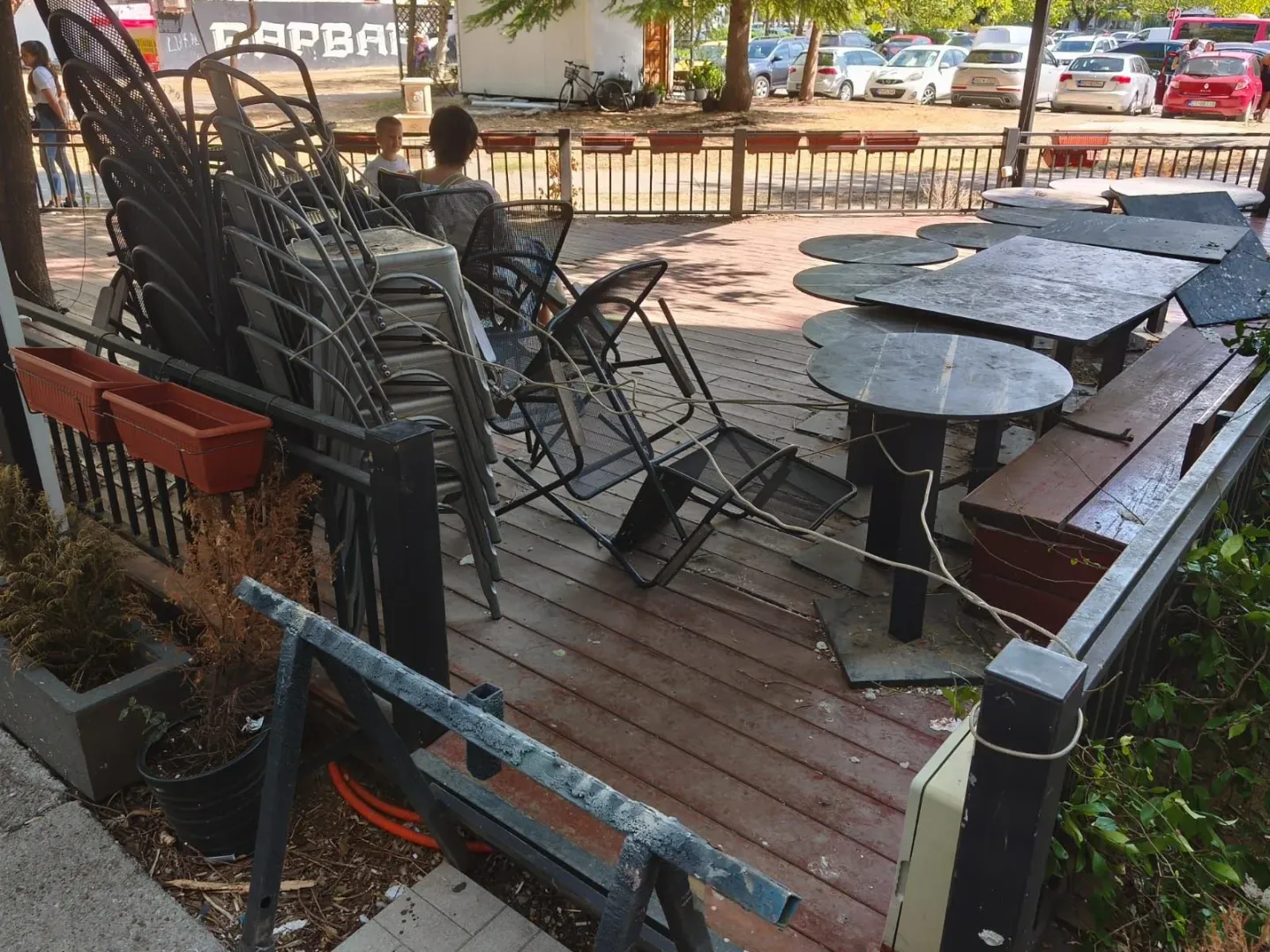 Terrace with a wooden deck, tables, and stacked chairs.