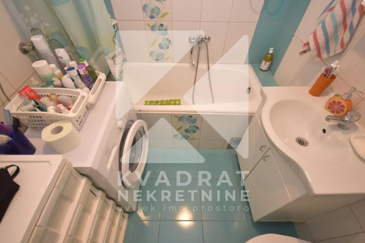 Kompaktno kupatilo opremljeno kadom, umivaonikom i veš mašinom.