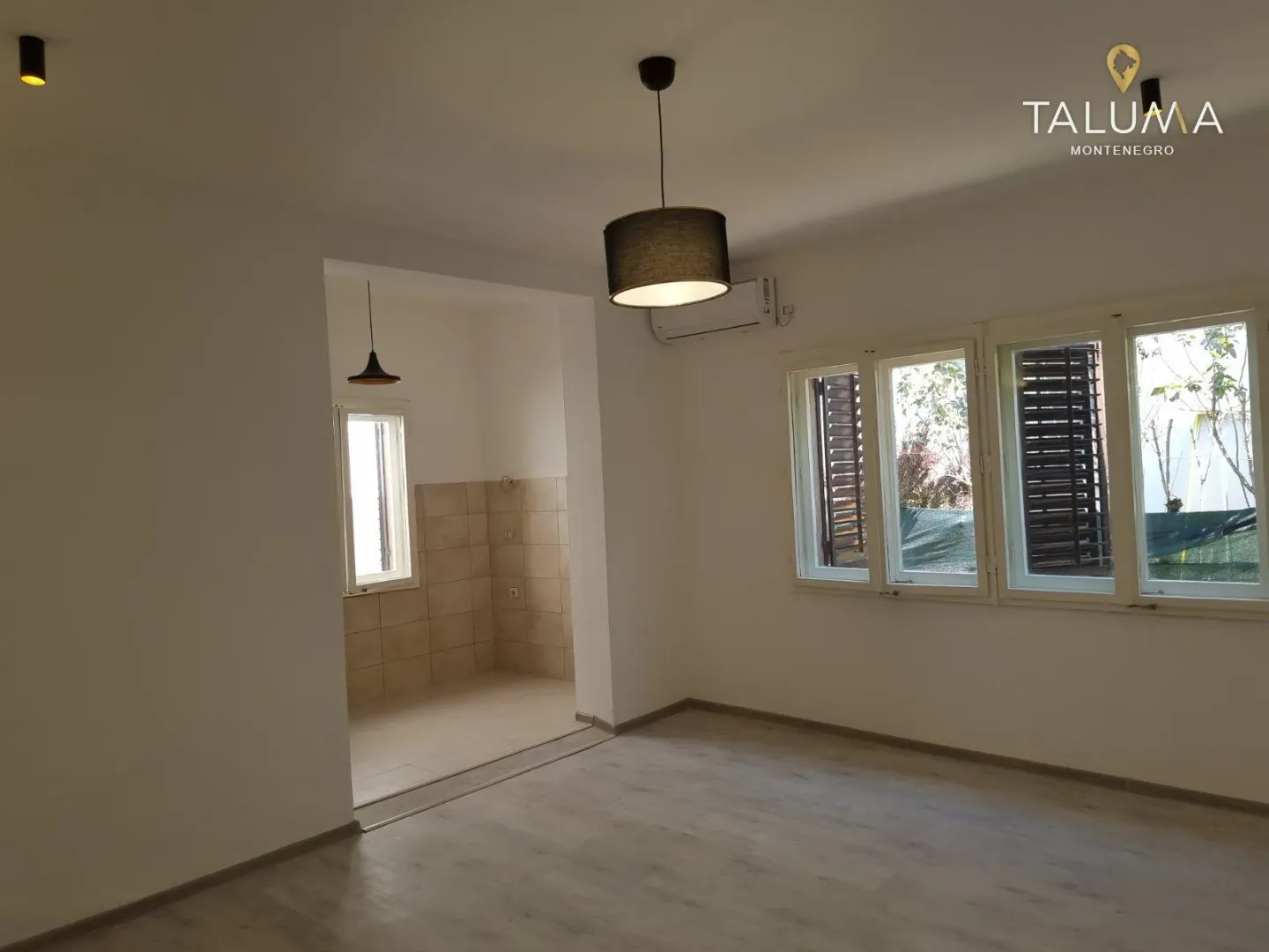 Empty living room with laminate flooring and views through the windows.