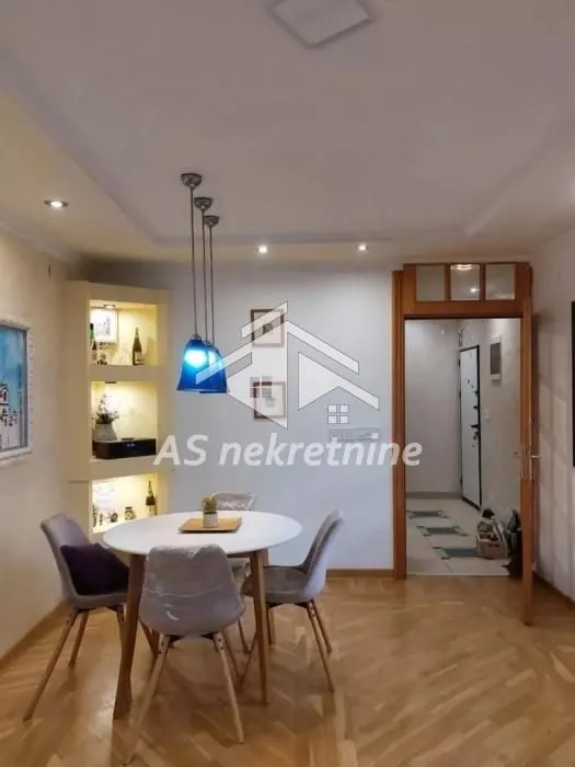 Trpezarija sa okruglim stolom i stolicama u sklopu dnevnog boravka.