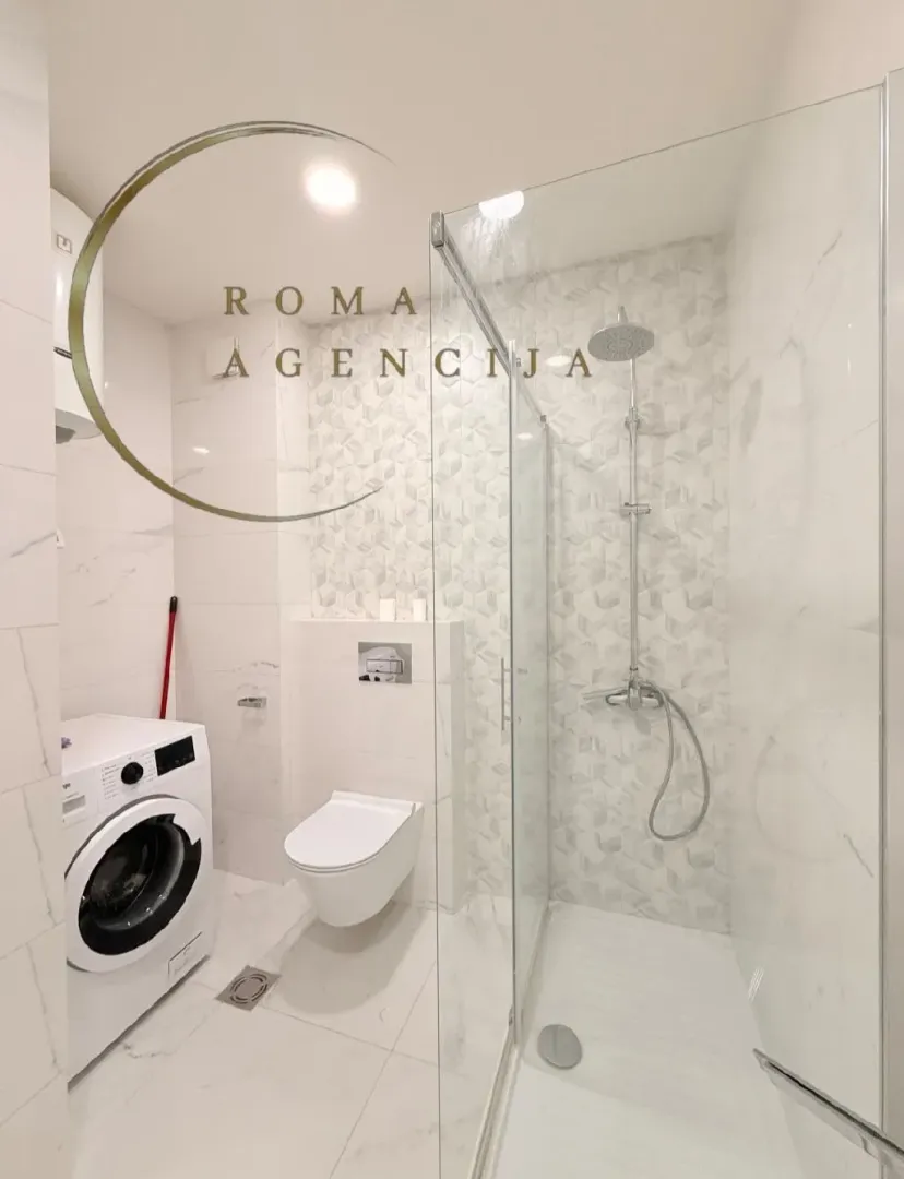 Moderne svijetlo kupatilo sa tuš kabinom, wc šoljom i veš mašinom.