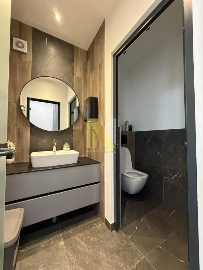 Modern bathroom equipped with a washbasin, mirror, and toilet in a separate section.