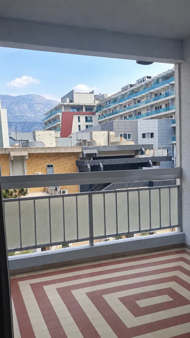 Pogled sa balkona na okolne zgrade i planine.