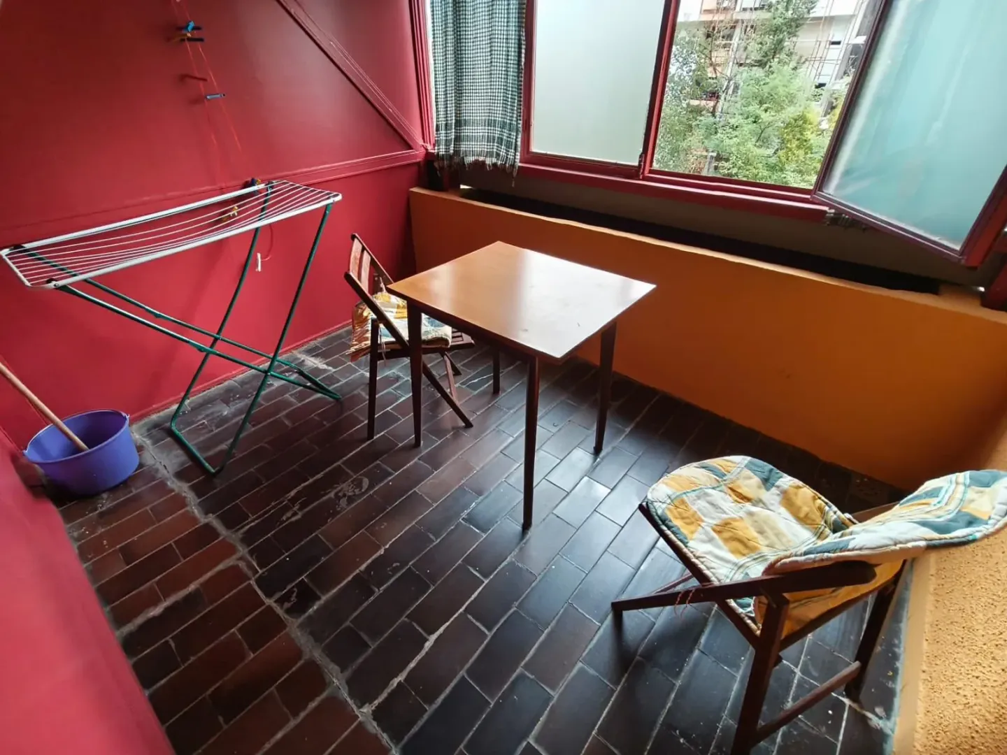 Natkriveni balkon sa stolom, stolicama i stalkom za sušenje veša.