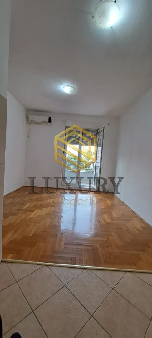 Prazna soba sa parketom i izlazom na terasu.