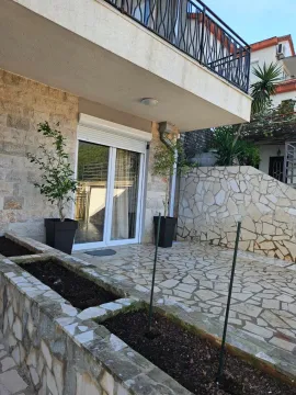 Popločano dvorište sa kamenom fasadom i balkonom iznad. - image 17