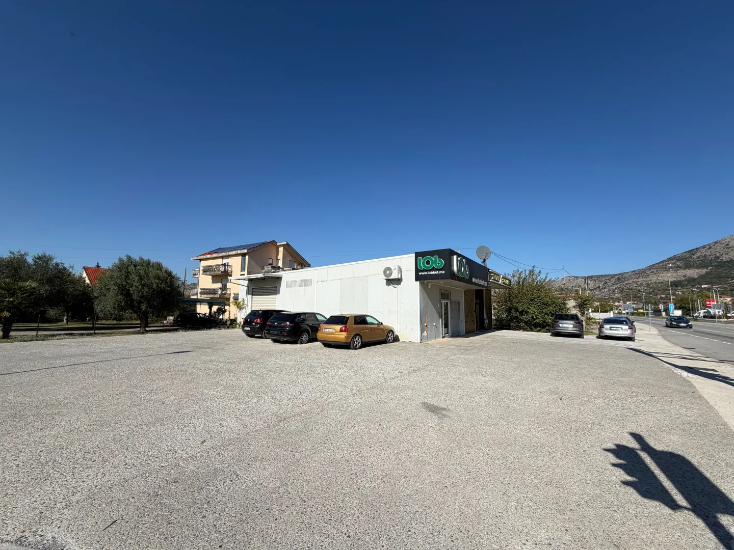 Exterior of a commercial building with a large parking lot and surrounding greenery.