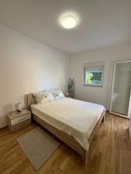 Svjetla spavaća soba sa bračnim krevetom, noćnim stočićem i ormarom. - image 5